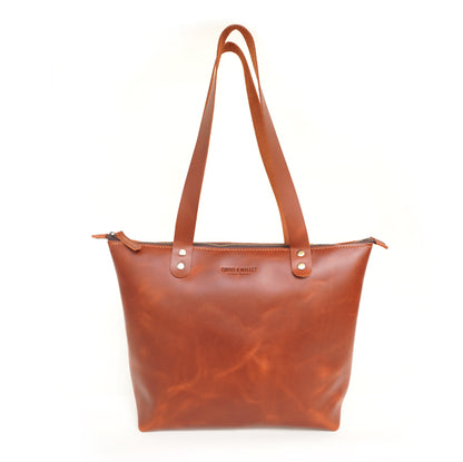 Brown leather tote bag with visible brand name on a white background