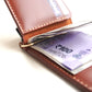 Brown leather wallet with Indian currency notes inside on a white background